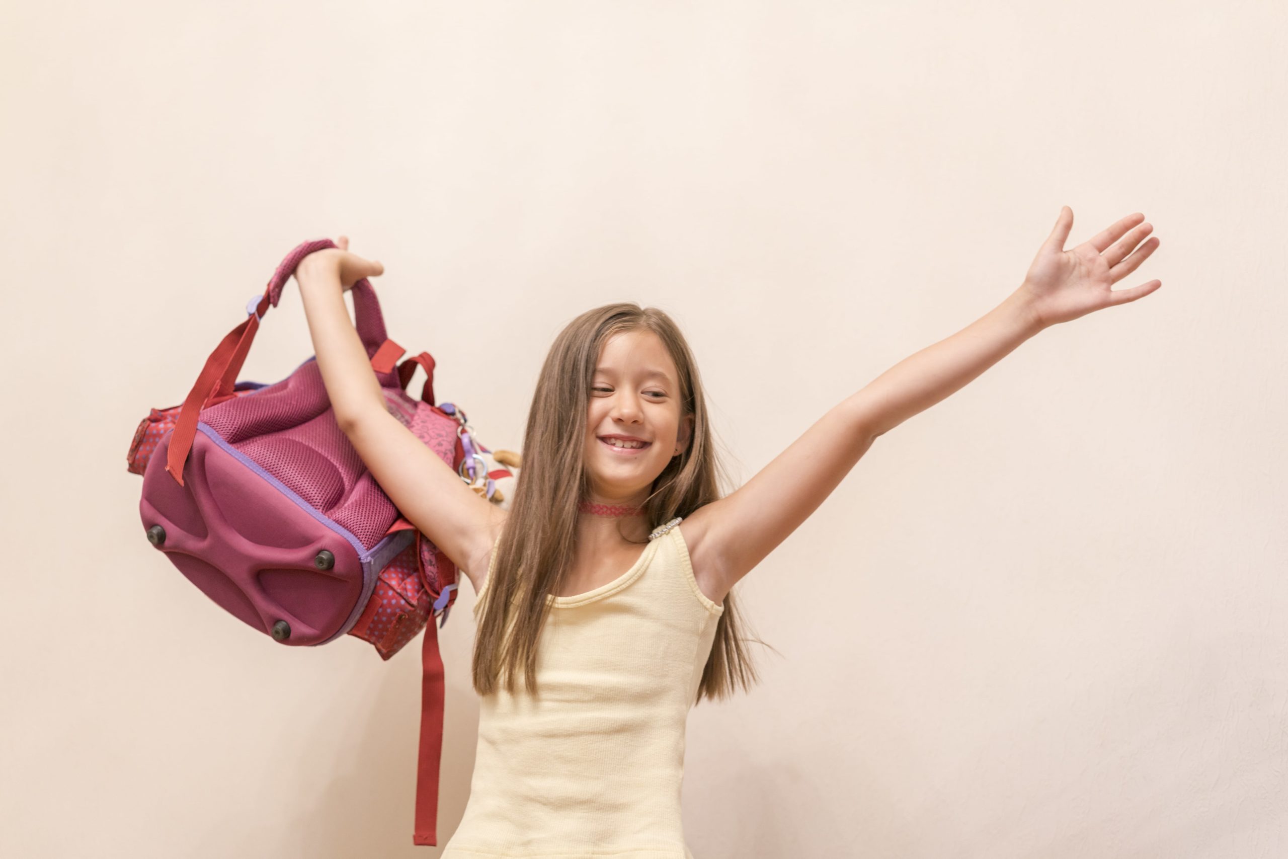 young girl celebrating with arms up and backpack